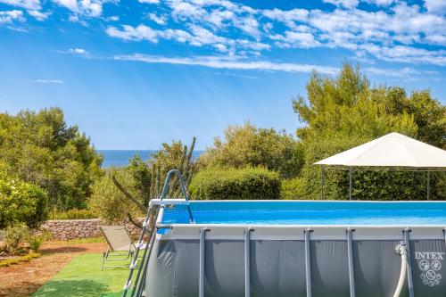 a swimming pool with an umbrella and a chair at Villa Marilor in Salve