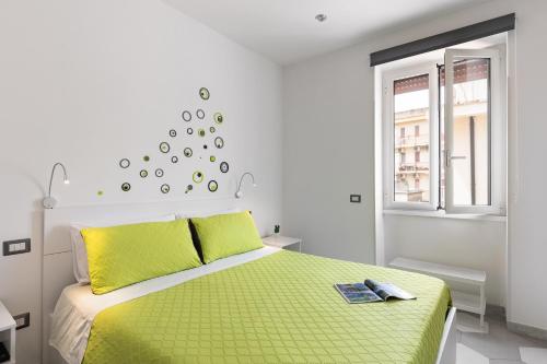 a white bedroom with a green bed and a window at Gaeta, B&B la Loggia in Gaeta
