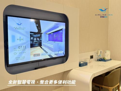a flat screen tv in a room with a white table at Airline Inn Green Park Way in Taichung