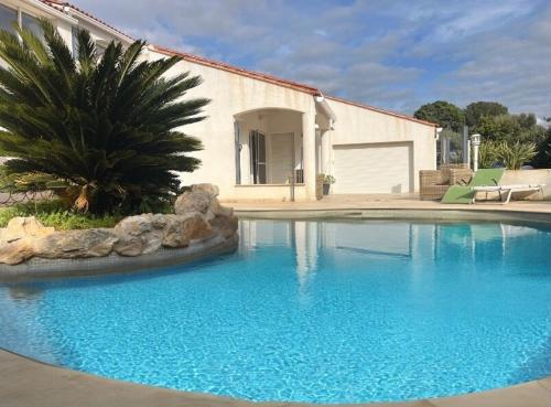 une grande piscine bleue devant une maison dans l'établissement Villa Marella, aux Lecques