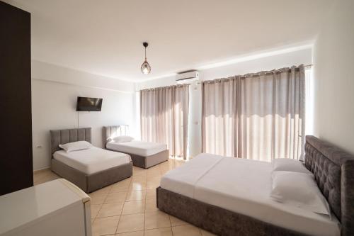 a hotel room with two beds and a couch at ALNES HOTEL in Sarandë