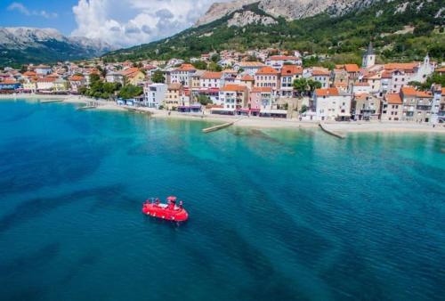 a red boat in the water next to a beach at VALI in Baška