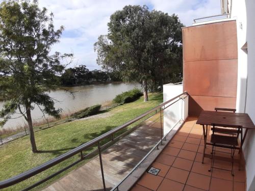 a balcony with a table and a view of a river at Casa do lago em Sol Tróia in Troia