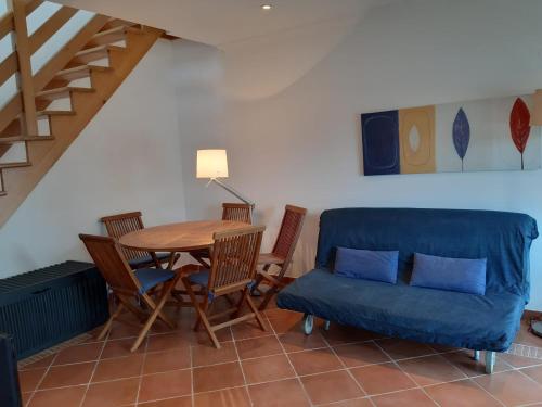 a dining room with a table and chairs and a blue couch at Casa do lago em Sol Tróia in Troia
