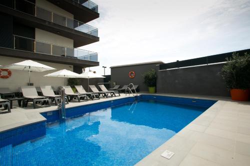 uma piscina com cadeiras e guarda-sóis ao lado de um edifício em Apartamentos Fuengirola Playa em Fuengirola