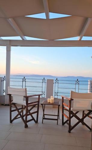 two chairs and a table on a balcony with the ocean at Wave Whisper Home in Vathí