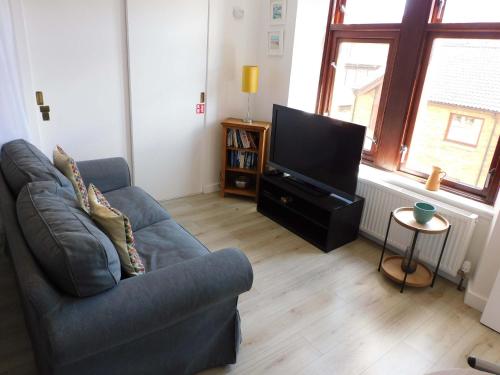 a living room with a couch and a flat screen tv at Modern bright studio apartment in south Glasgow in Glasgow