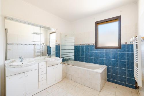 a bathroom with two sinks and a bath tub and a window at Grande maison familiale proche gr34 in Garlan