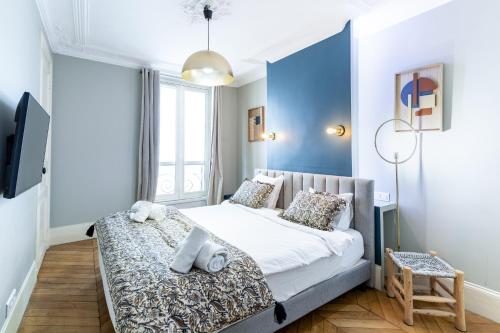 une chambre avec un lit et un mur bleu dans l'établissement COSY APPARTMENT IN THE HEART OF PARIS, à Paris