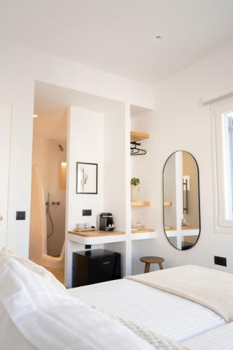 a white bedroom with a bed and a mirror at Eleana Hotel in Tinos Town