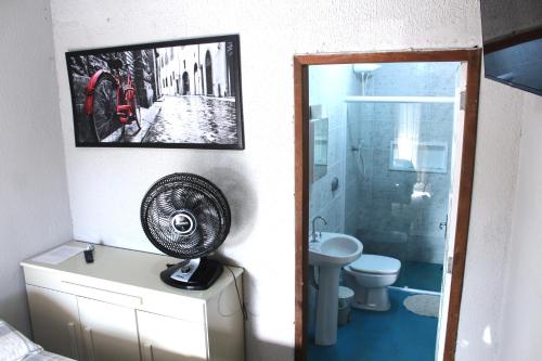 a bathroom with a shower and a sink and a fan at Pousada Captain Morgan Pontal do Sul com Piscina in Pontal do Paraná