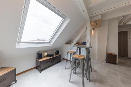 une chambre mansardée avec deux tabourets et une fenêtre dans l'établissement Le Petit Schilik - Proche de Strasbourg, à Schiltigheim