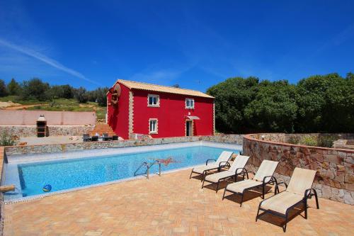 einen Pool mit Stühlen und ein rotes Haus in der Unterkunft Quinta dos Vales Wine Estate in Estômbar