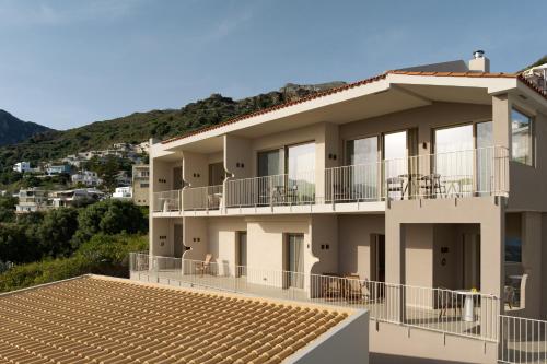 an apartment building with balconies and a mountain at Stella in the Village Suites in Plakias