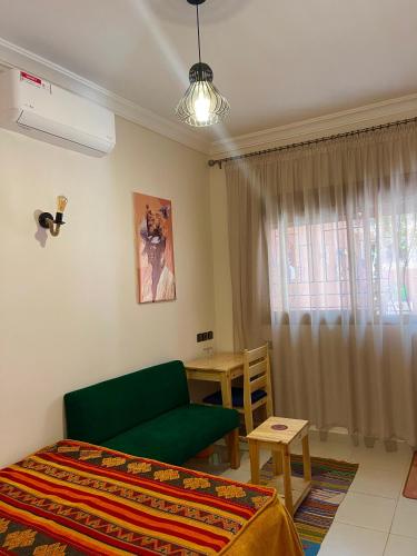 a bedroom with a green couch and a table at Dyafat Abla in Ouarzazate