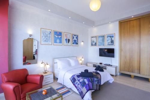 a bedroom with a bed and a chair and a television at Villa Paquet - Quartier Art Déco in Casablanca