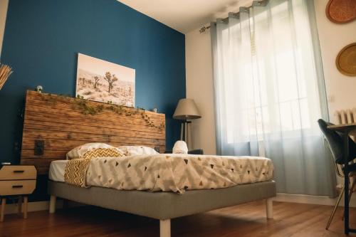 une chambre avec un lit et un mur bleu dans l'établissement Au Petit Pelloutier, à Albi
