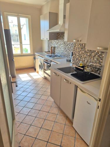 Il comprend une cuisine avec des appareils électroménagers blancs et du carrelage. dans l'établissement Appartement spacieux - 60 m2 - calme, à Perpignan