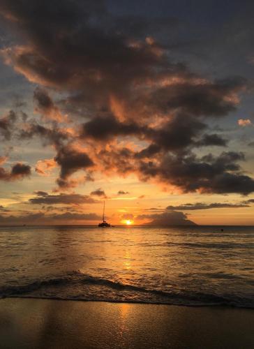 a sunset on the beach with a boat in the water at Bord Mer Villa in Beau Vallon