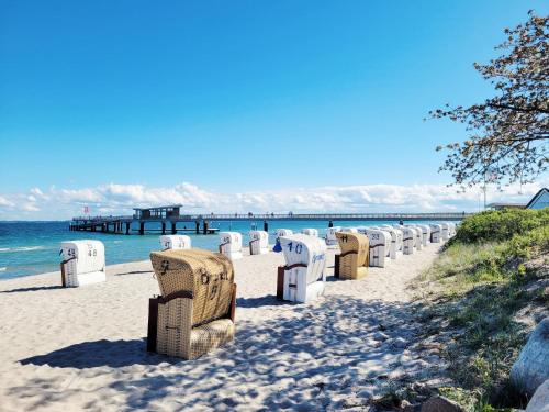 a row of chairs on a beach with a pier at Moderne Ferienunterkunft in ruhiger Lage und nur 7 Gehminuten vom Strand entfernt - hoher Schlafkomfort und Gartenzugang für die ideale Erholung an der Ostsee in Scharbeutz