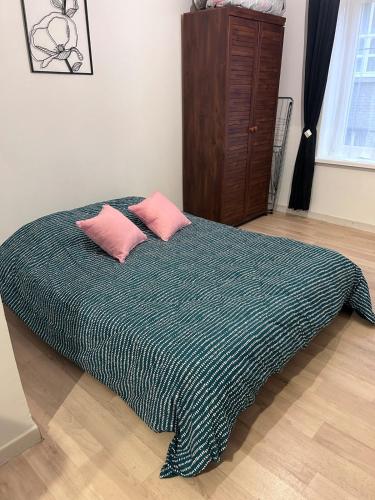 - un lit avec 2 oreillers roses dans l'établissement Pause Confort Studio idéal centre ville, à Gravelines