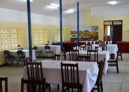 a dining room with white tables and chairs at Mgulani Lodge Hotel in Dar es Salaam