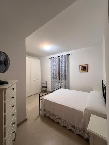 a white bedroom with a bed and a window at Villa Althea in Piombino