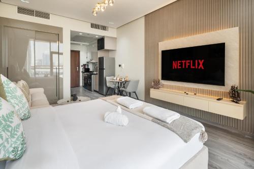 a bedroom with a bed with a television on a wall at Trendy Studio Apartment in Binghatti Crystals in Dubai