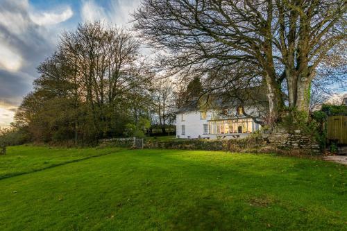 a large yard with a white house and a tree at Trenderway Farm in Looe