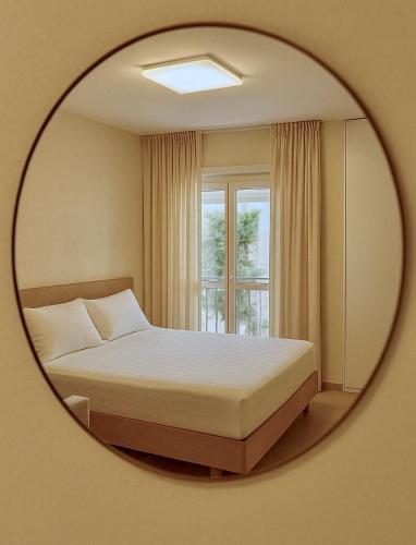 a mirror reflecting a bedroom with a bed and a window at PROMO Cozy Apartments in Golem