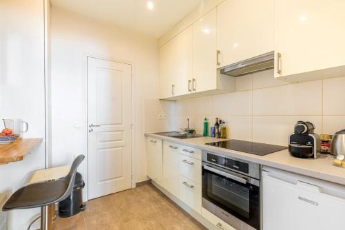 une cuisine avec des armoires blanches et un four à plaques de cuisson dans l'établissement GuestReady - Stylish comfort near Montsouris, à Paris
