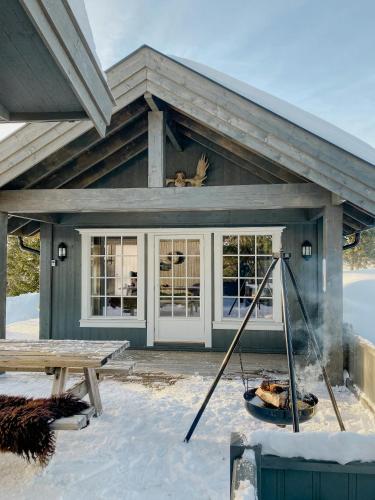 a house with a fireplace in the snow at Cozy Modern Cabin Near Sjusjøen in Mesnali