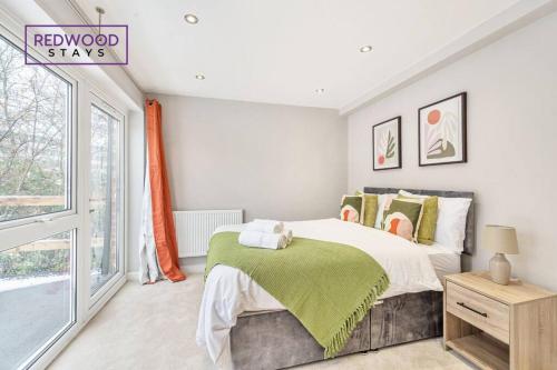a bedroom with a bed with a green blanket on it at Huge 5 Bed 3 Bath House For Contractors & Families, 2X Free Parking, Free WiFi & Netflix By Redwood Stays in Farnborough