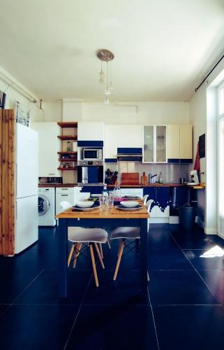 une cuisine avec une table en bois et des appareils électroménagers blancs dans l'établissement Au Petit Pelloutier, à Albi
