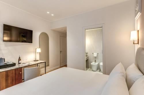 a white bedroom with a bed and a bathroom at Hotel Fori Imperiali in Rome