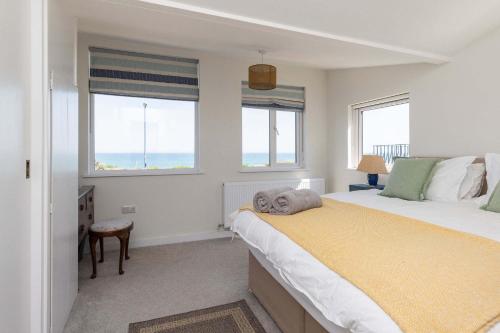 a bedroom with a bed and two windows at Historic Railway Home - Selsey Seafront in Selsey