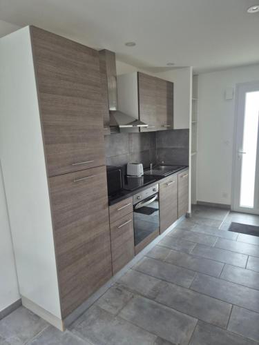 une cuisine avec des armoires en bois et un comptoir dans l'établissement Gite de l'usine, à Roussay