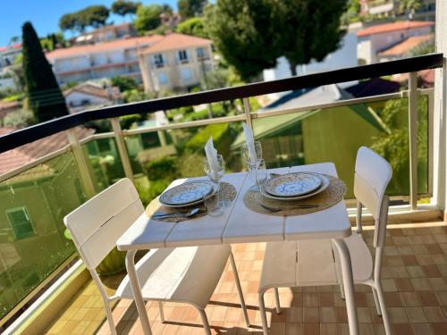 une table blanche et des chaises sur un balcon dans l'établissement Les CAMELIAS, à Antibes