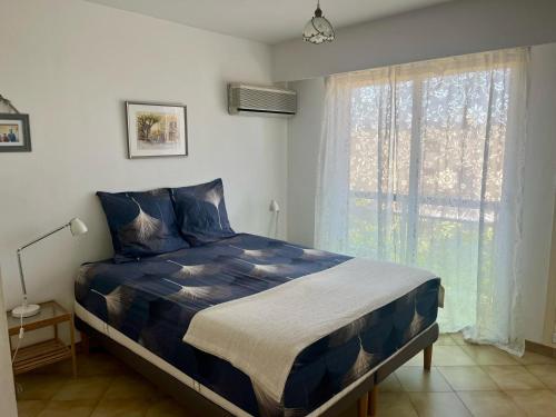 une chambre avec un lit bleu avec une fenêtre dans l'établissement Les CAMELIAS, à Antibes