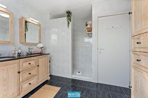 un bagno con doccia, lavandino e specchio di Groenhage - enjoy peace in the heart of Leffinge a Middelkerke