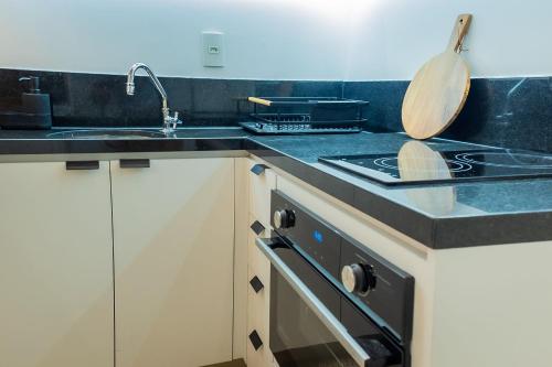 a kitchen with a sink and a stove with a wooden spoon at 1106 - Estúdio novíssimo com estrutura e conforto in Guarulhos