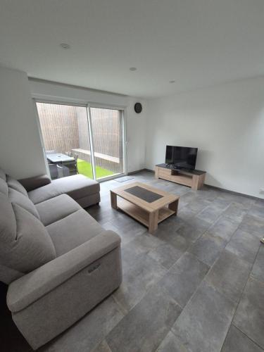 Una sala de estar con un sofá y un televisor. en Gite de l'usine, en Roussay