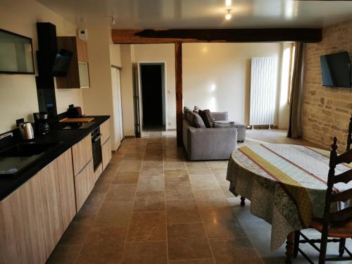 a kitchen and living room with a table and a couch at La Maison d'Hortense au coeur du vignoble in Saint-Bris-le-Vineux