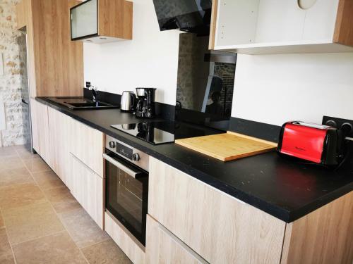 a kitchen with a black counter top and white cabinets at La Maison d'Hortense au coeur du vignoble in Saint-Bris-le-Vineux