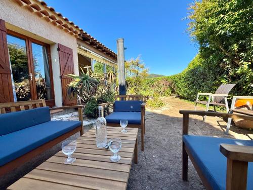 un patio avec deux bancs bleus et des verres à vin dans l'établissement Maison provençale - Plage 500m, à Carqueiranne