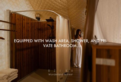 a woman standing in a bathroom with a shower at BZIKA Wonderland Retreat--Zhangjiajie National Forest Park Store in Zhangjiajie
