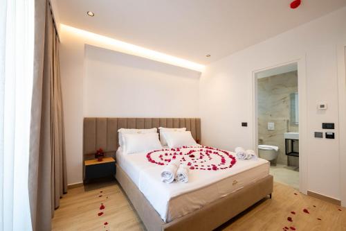 a bedroom with a large bed with red flowers on it at Alpaso Hotel in Sarandë