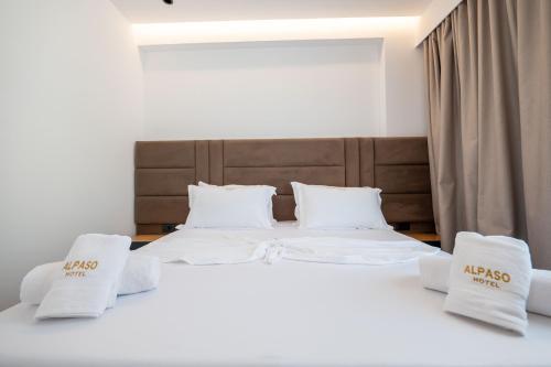 two beds in a room with white sheets and pillows at Alpaso Hotel in Sarandë