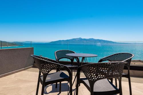 a table and chairs on a balcony with a view of the water at Alpaso Hotel in Sarandë