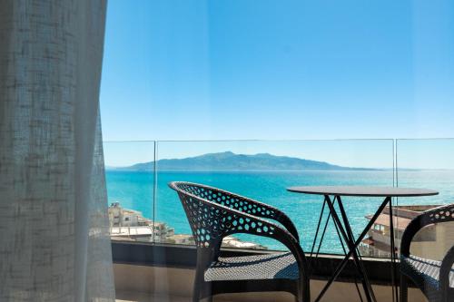 a table and chairs on a balcony with a view of the ocean at Alpaso Hotel in Sarandë